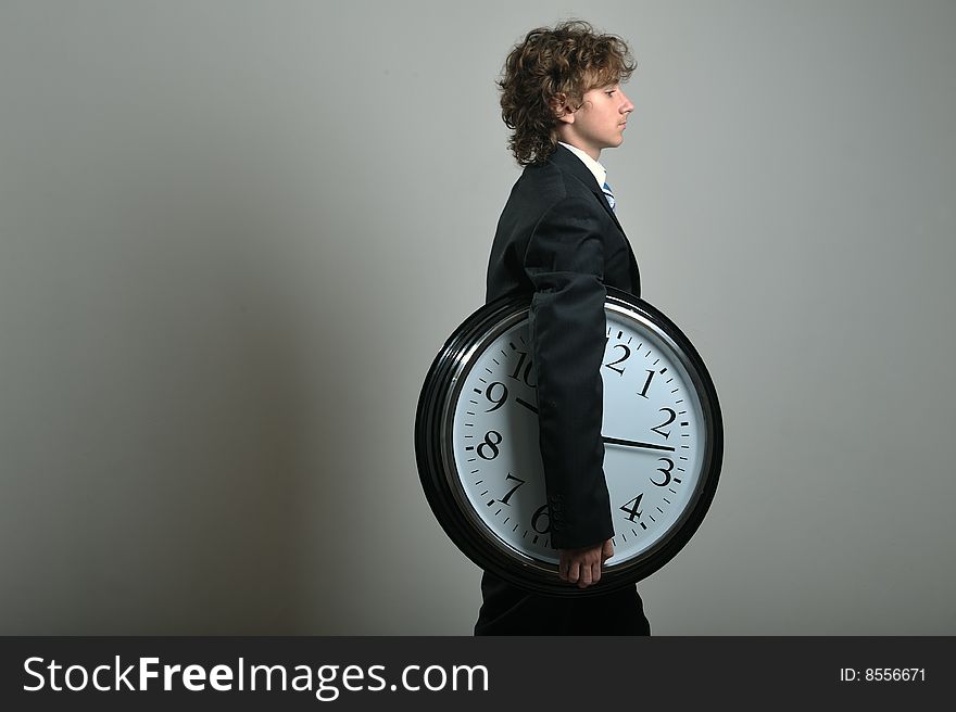 Young businessman holding a big clock in hands, deadline concept. Young businessman holding a big clock in hands, deadline concept