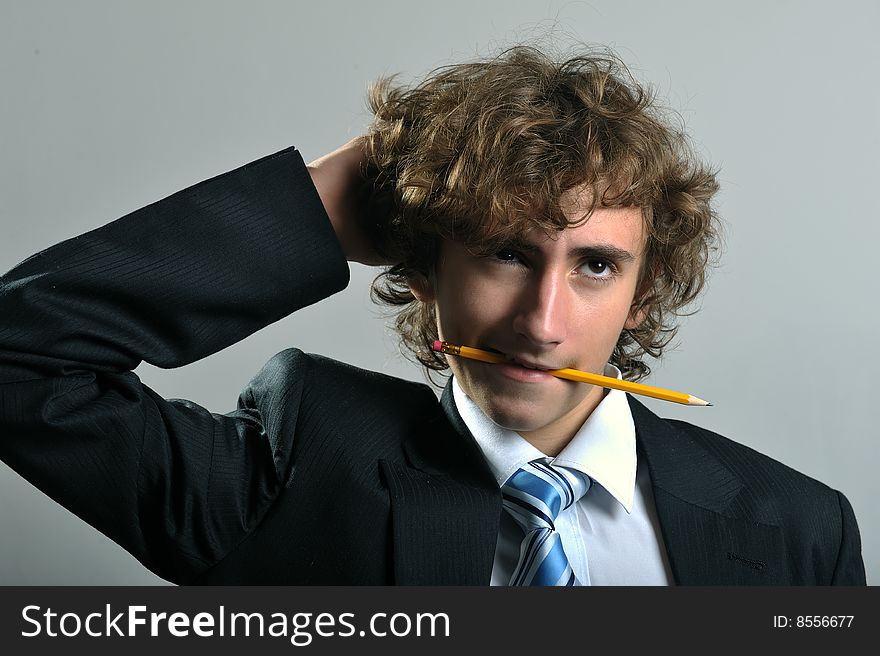 Young businessman holding a pencil in his mouth. Young businessman holding a pencil in his mouth