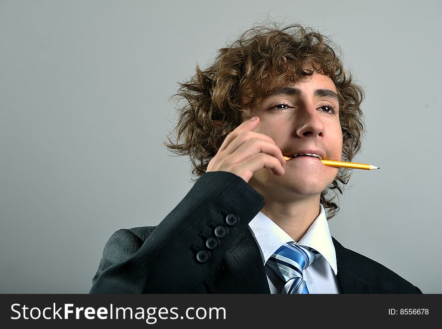 Young businessman holding a pencil in his mouth. Young businessman holding a pencil in his mouth