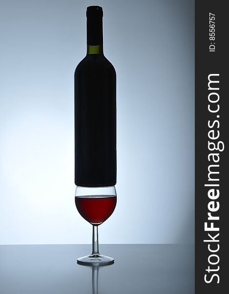 Bottle of red wine standing in equilibrium on a wineglass
