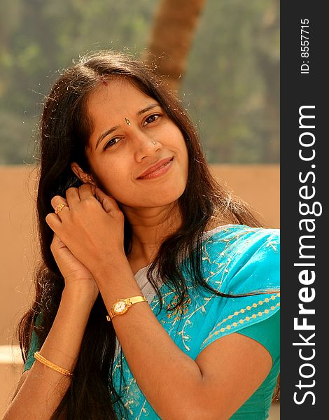 A smart and beautiful Indian woman fixing her earrings.