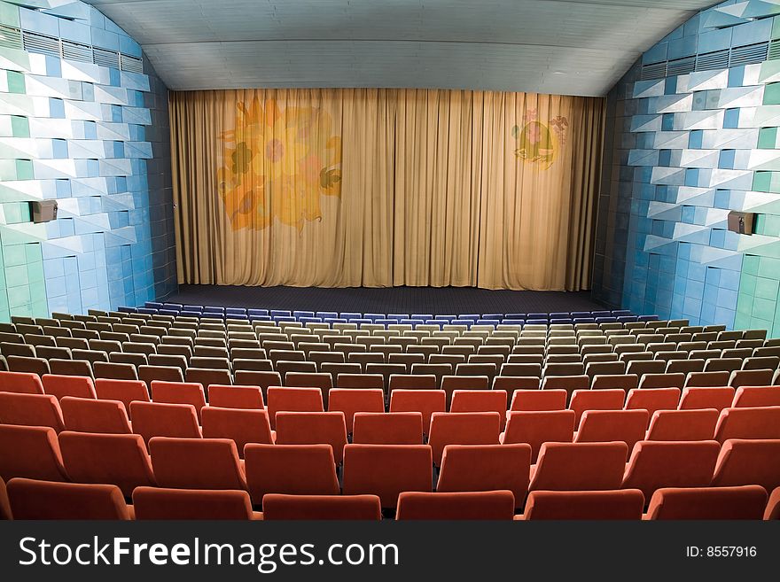 Empty cinema auditorium with line of chairs and stage with silver screen. Empty cinema auditorium with line of chairs and stage with silver screen.