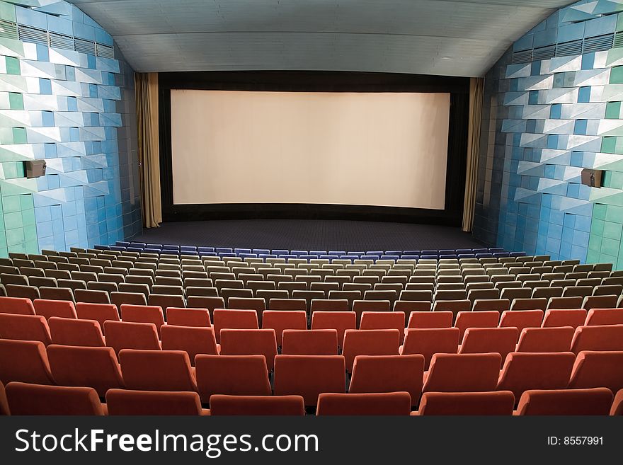 Empty cinema auditorium with line of chairs and stage with silver screen. Ready for adding your own picture. Empty cinema auditorium with line of chairs and stage with silver screen. Ready for adding your own picture.