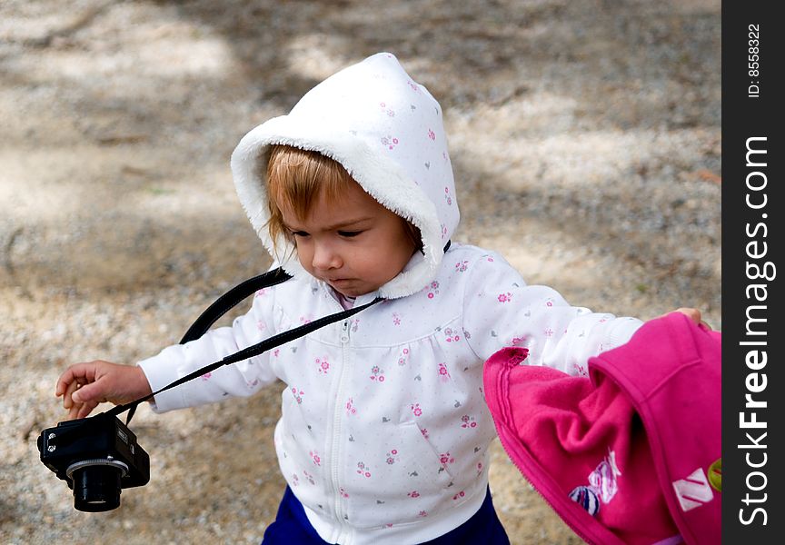 A young girl running with a compact digital camera and a red jacket in hand. A young girl running with a compact digital camera and a red jacket in hand