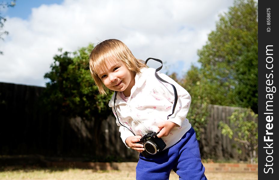 A young girl playing with a compact digital camera. A young girl playing with a compact digital camera