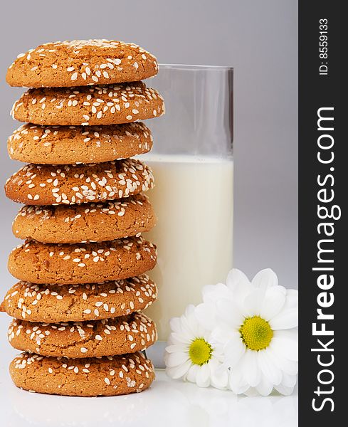 Cookies with sesame, milk and daisies over grey. Cookies with sesame, milk and daisies over grey