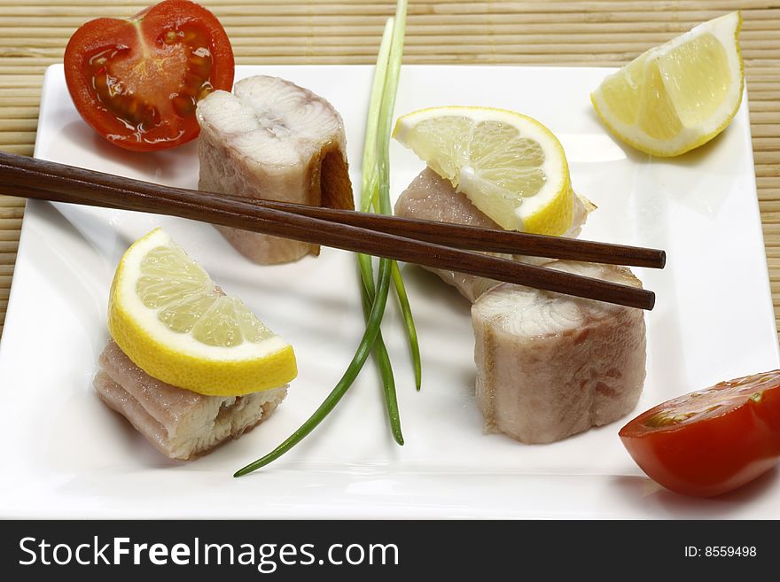 Pieces of smoked eel on a plate with garnish. Pieces of smoked eel on a plate with garnish