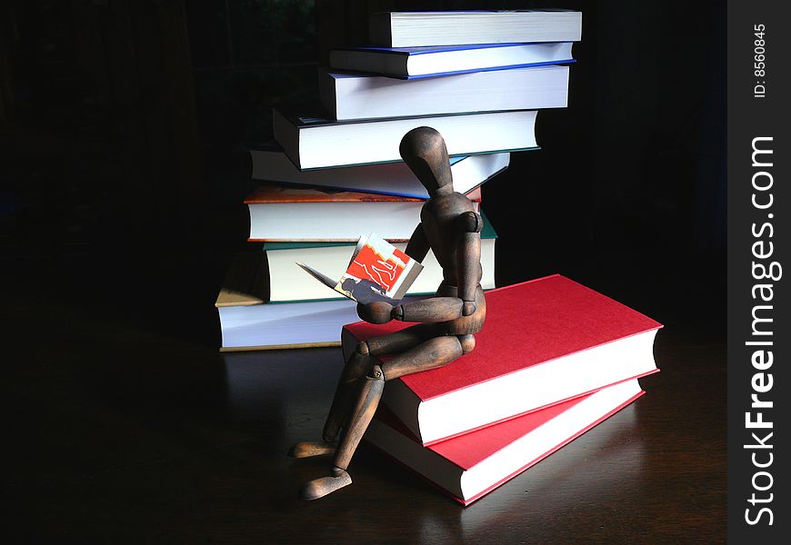 A doll of wood sitting on books. A doll of wood sitting on books