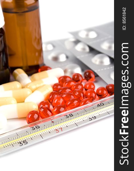 Thermometer and different pills closeup on white background. Thermometer and different pills closeup on white background