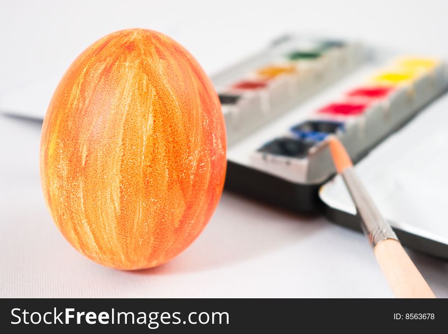 Easter egg fresh painted with brush and watercolor palette in background. Easter egg fresh painted with brush and watercolor palette in background.