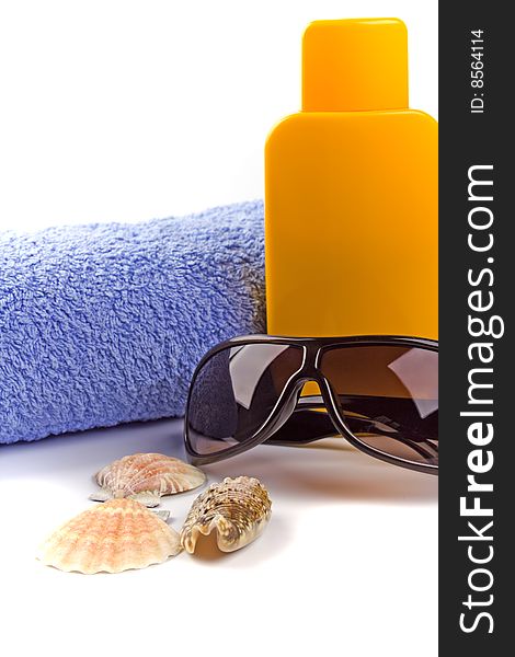 Towel, sunglasses and lotion closeup on white background