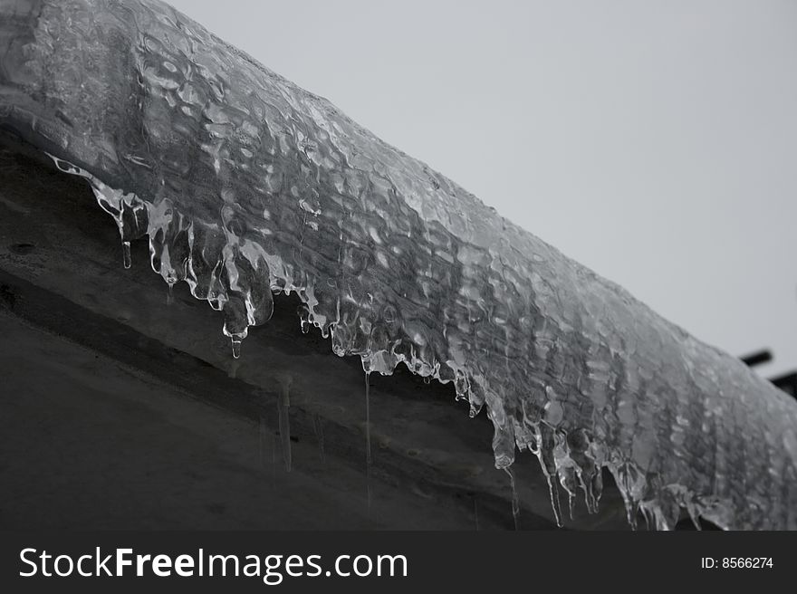 Icicles form on gray concrete edge. Frozen clear water. Icicles form on gray concrete edge. Frozen clear water.