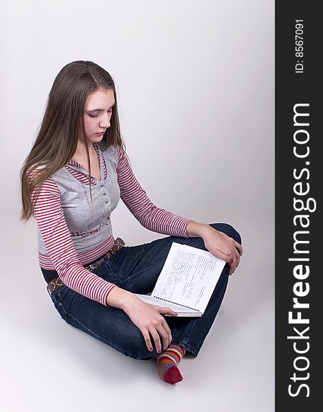 Teenage Girl sitting and reading school lesson, over gray background. Teenage Girl sitting and reading school lesson, over gray background.