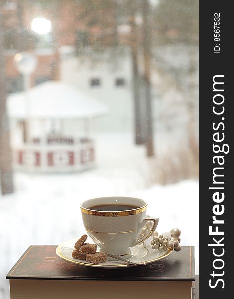 Porcelain cup with coffee on a stack of books by the window. Porcelain cup with coffee on a stack of books by the window