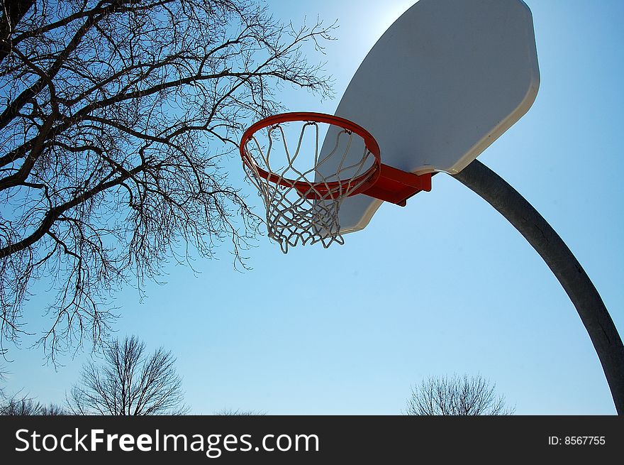An image of a basketball hoop under the sun.