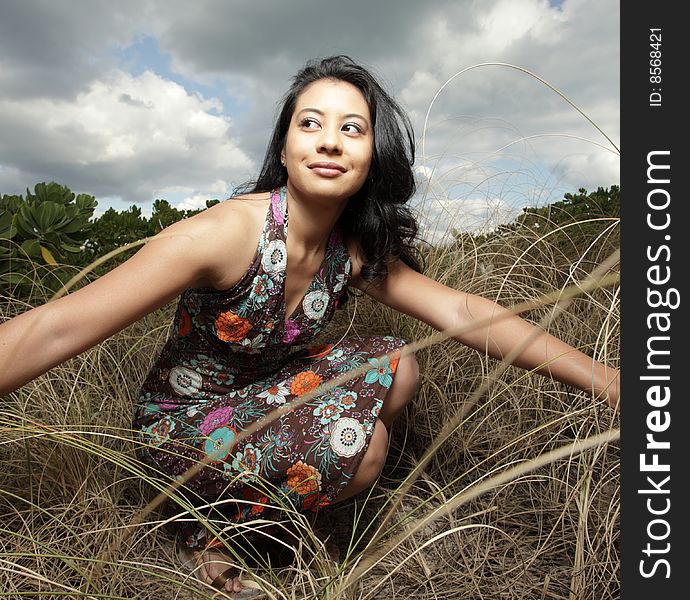 Young woman squatting down in a field of dunes. Young woman squatting down in a field of dunes