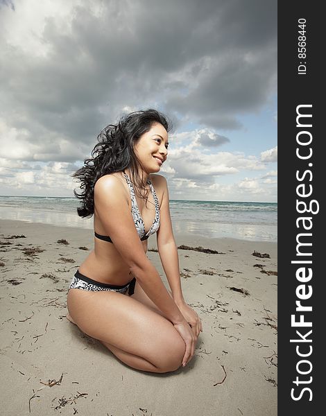 Young woman squatting on the beach sand. Young woman squatting on the beach sand