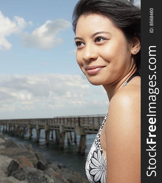 Woman smiling with a rock formation and pier in the background. Woman smiling with a rock formation and pier in the background