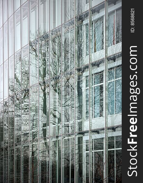 Office building facade, with trees reflected in the glass.