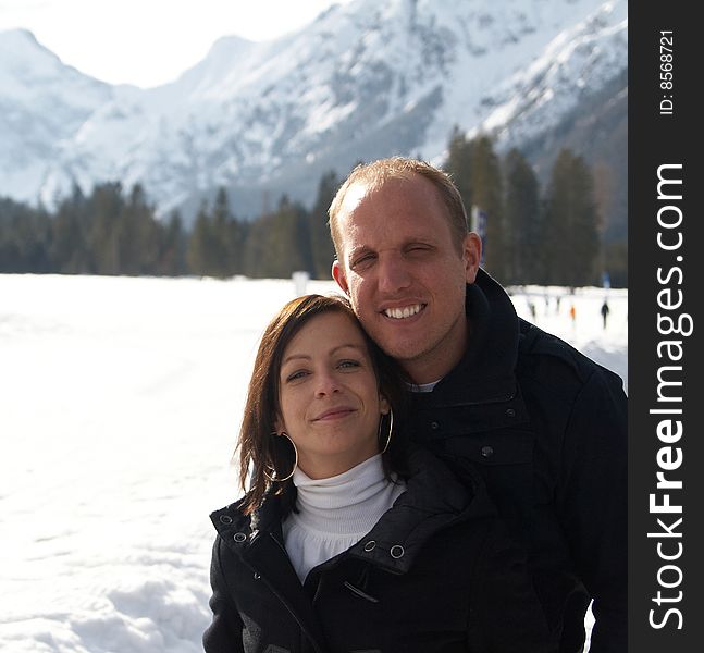 A young couple outdoor in a winter setting. The couple is hugging each other. A young couple outdoor in a winter setting. The couple is hugging each other.