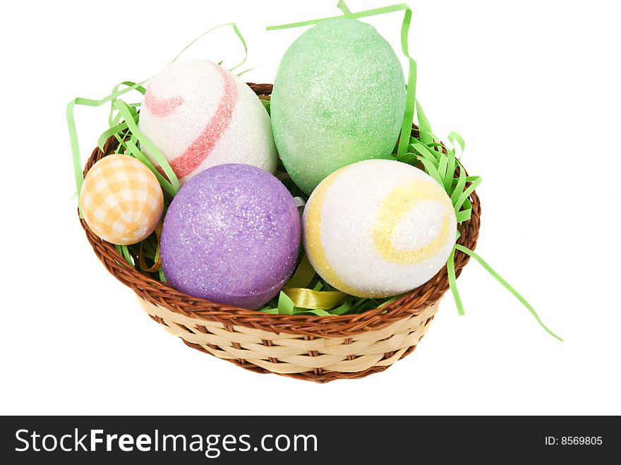 Colored Easter eggs in a basket with green grass isolated on white background