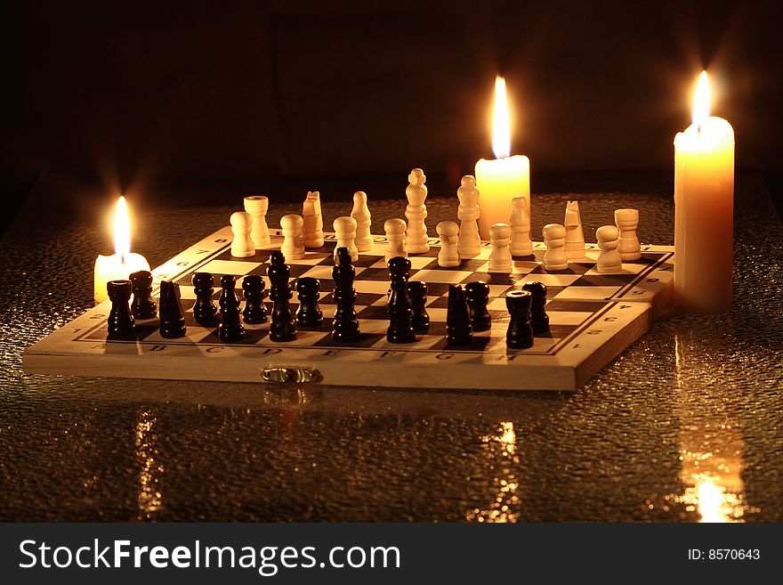 Chess on dark background with burning candles. Chess on dark background with burning candles