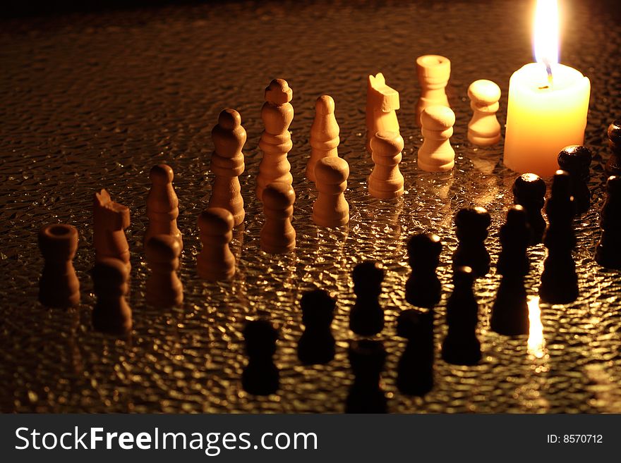 Chess on dark background with burning candle. Chess on dark background with burning candle
