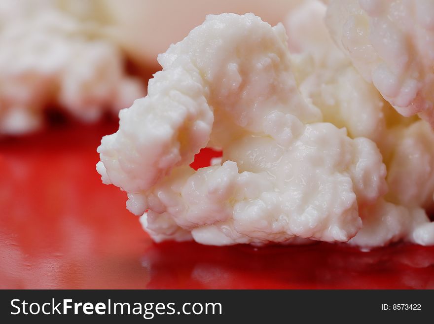 Cottage cheese on the red plate. Close-up. Narrow depth of field. Cottage cheese on the red plate. Close-up. Narrow depth of field.