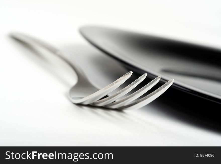 Fork and black plate on white background. Fork and black plate on white background