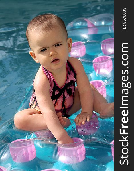 Curious baby sitting on an inflatable raft in a swimming pool. Curious baby sitting on an inflatable raft in a swimming pool