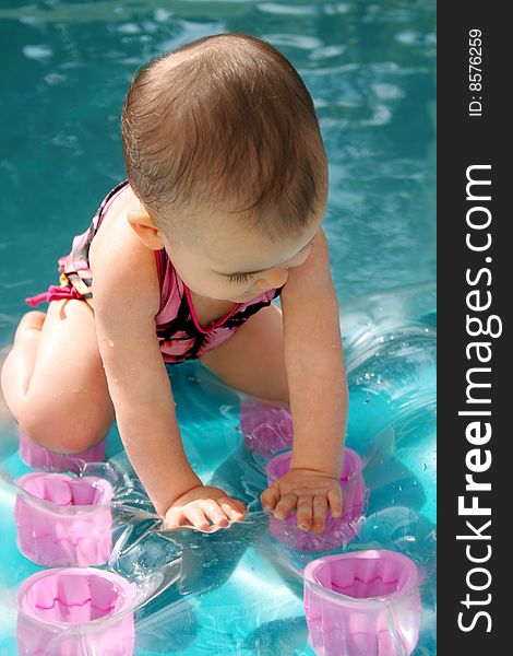 Baby balancing on an inflatable raft in a swimming pool. Baby balancing on an inflatable raft in a swimming pool
