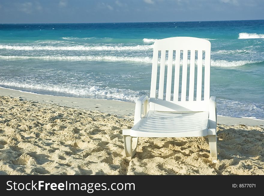 White plastic long chair on a sandy beach