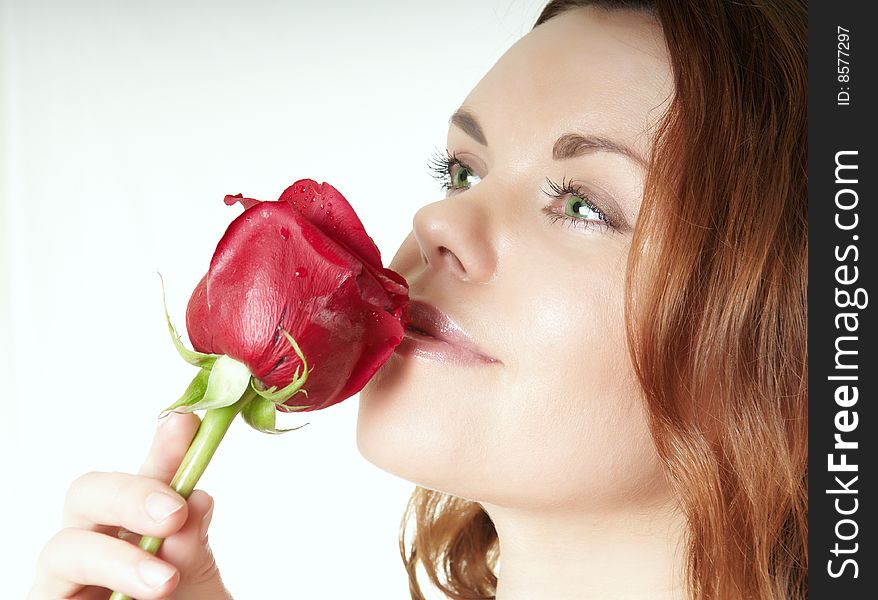 The beautiful girl smells a red fresh rose. The beautiful girl smells a red fresh rose