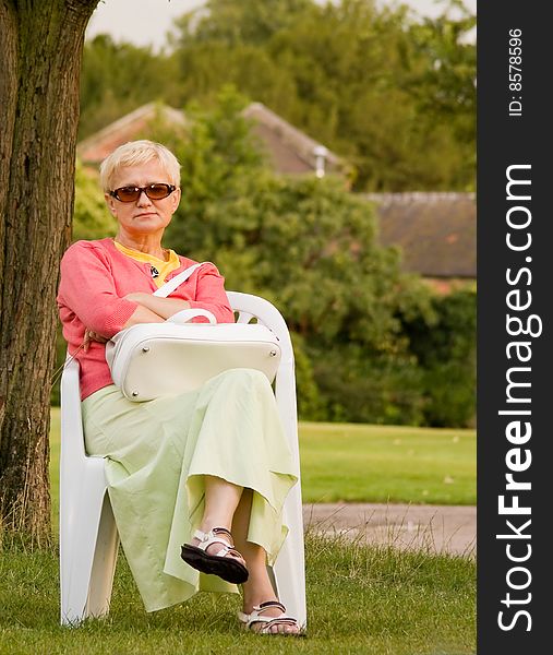 Woman sitting on the chair; evening in the garden. Woman sitting on the chair; evening in the garden.