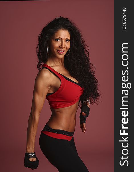 A fitness model  with long flowing hair in studio  wearing a black and red workout outfit with  gloves and ear rings. A fitness model  with long flowing hair in studio  wearing a black and red workout outfit with  gloves and ear rings.