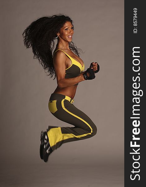 A fitness model with long flowing hair in studio wearing a green and yellow workout outfit with gloves and ear rings. A fitness model with long flowing hair in studio wearing a green and yellow workout outfit with gloves and ear rings.