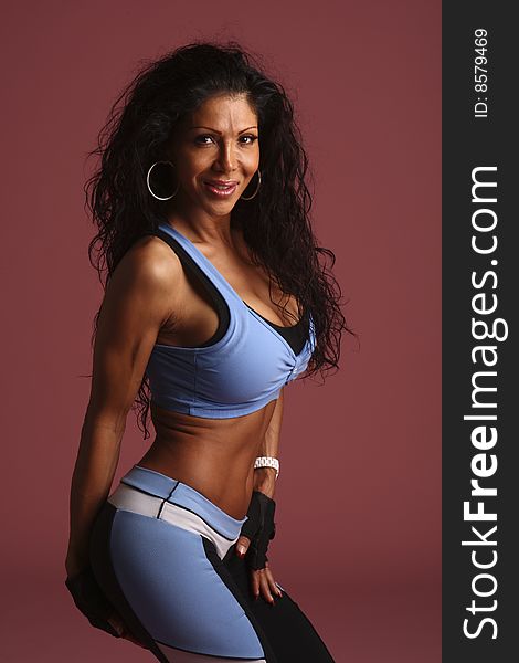 A fitness model  with long flowing hair in studio  wearing a blue, white, and black workout outfit with  gloves and ear rings. A fitness model  with long flowing hair in studio  wearing a blue, white, and black workout outfit with  gloves and ear rings.