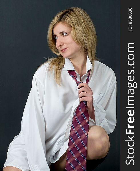 Beautiful blond girl with long shirt and necktie sitting. Beautiful blond girl with long shirt and necktie sitting