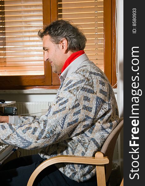 An elderly man at work with his computer at home