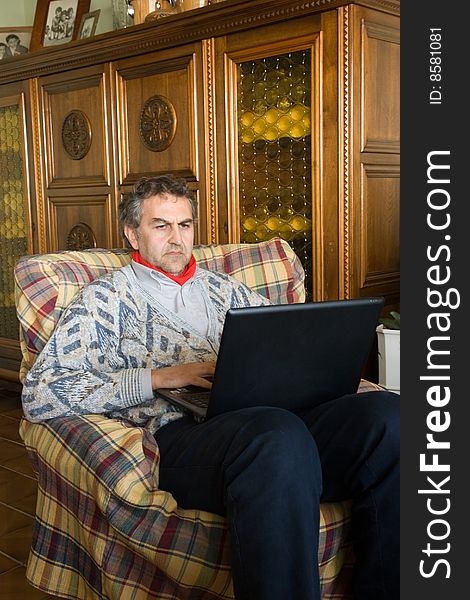 An elderly man at work with his computer at home