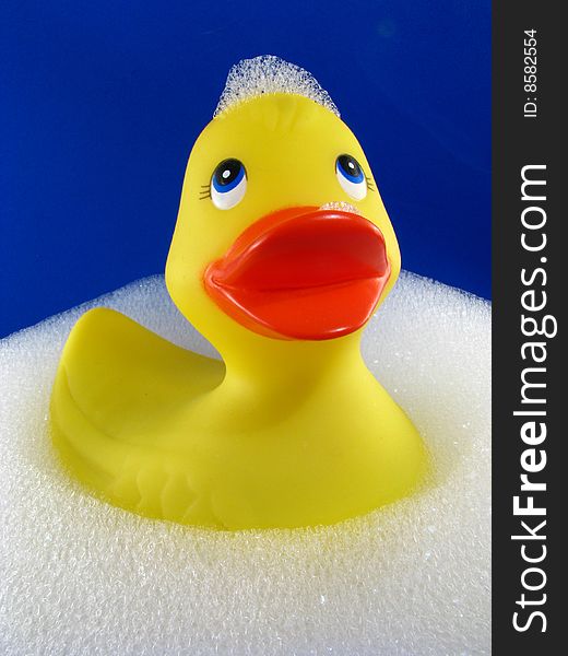 A rubber ducky floating in a bubble bath with a blue background. A rubber ducky floating in a bubble bath with a blue background