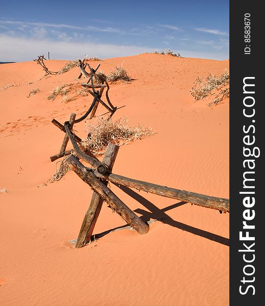 A log pole fence is slowly being engulfed by drifting sand. A log pole fence is slowly being engulfed by drifting sand