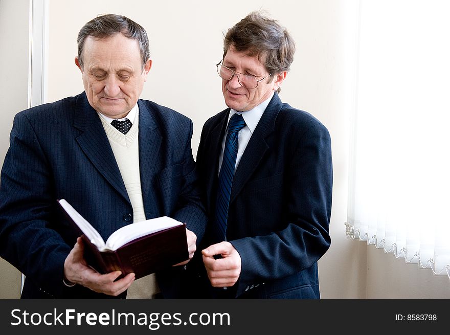 Portrait of a two senior businessmen reading the book