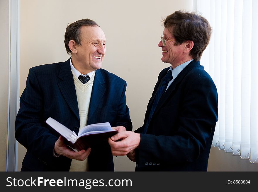 Portrait of a two senior businessmen reading the book