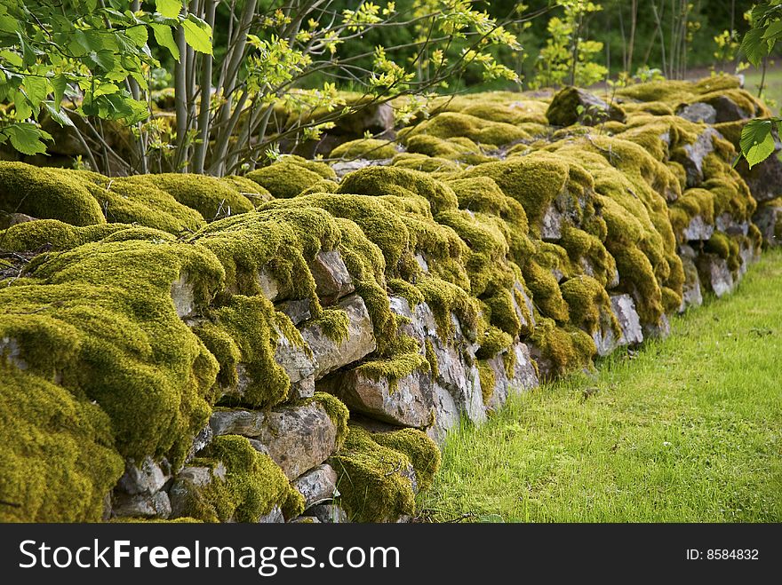 An old mossy stone wall near a chapel.