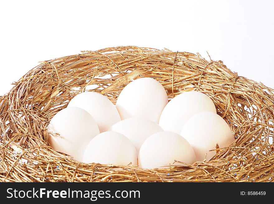 White eggs in golden nest on white