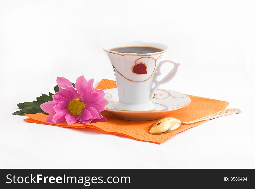 Cup of black coffee and lilac flower on orange napkin. Cup of black coffee and lilac flower on orange napkin