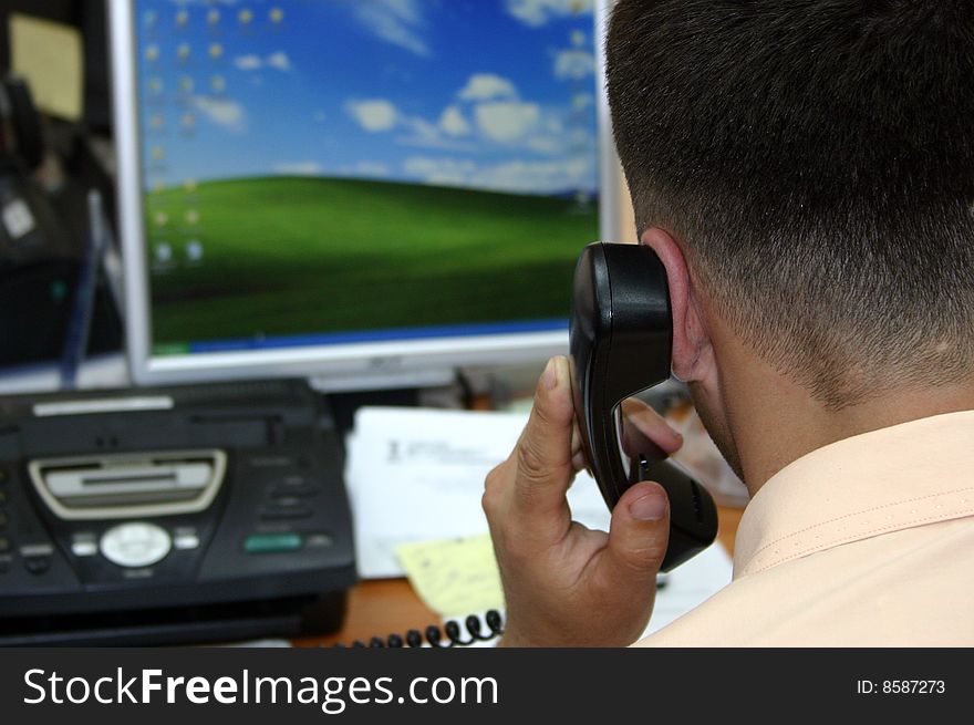 A regular office scene. Businessman speaking at the phone.