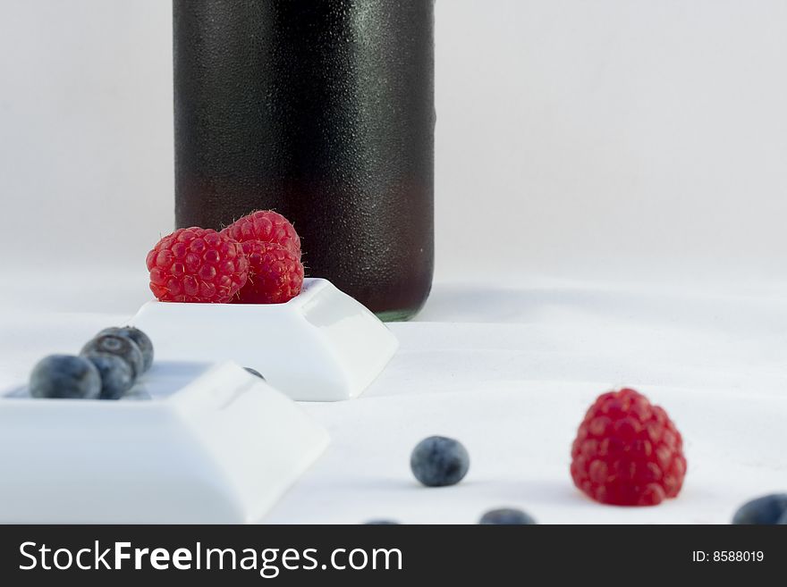 Raspberries, blueberries and a botle of wine studio isolated on a white background