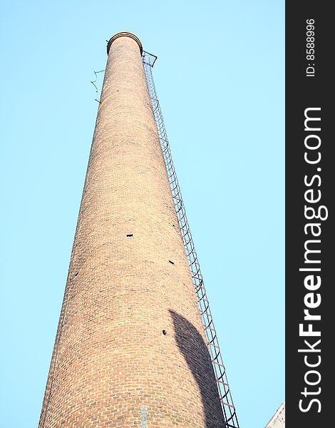 Industrial smokestack under blue sky.